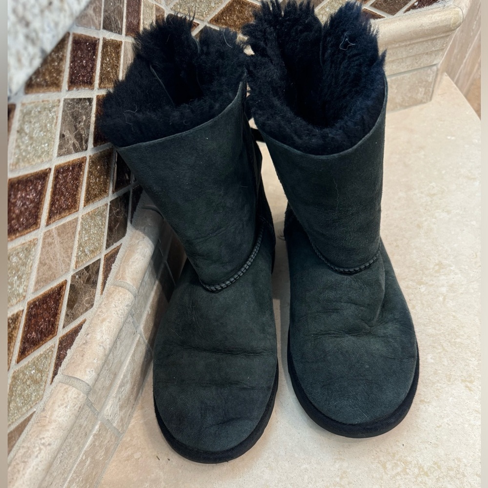 Women’s size 6, faded black UGGs with bows on the back